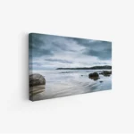 لوحات مناظر طبيعية تعكس سكون البحر تحت سماء غائمة، مع صخور تتناثر على الشاطئ. لوحات فخمة، لوحات جدارية للمنزل، لوحات أنيقة.