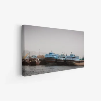 لوحة بحرية لسفن تقليدية بألوان زرقاء وبنية تحت ضباب خفيف، تعكس أجواء هادئة، لوحات طبيعة، لوحات كانفاس.