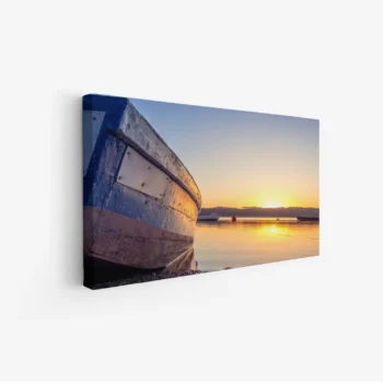 لوحة بحرية تظهر قاربًا قديمًا بلون أزرق مع غروب الشمس الدافئ وانعكاساته على الماء، لوحات جمادات ومعالم، لوحات كانفاس.