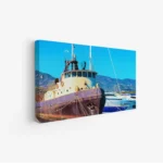 لوحة بحرية تظهر قاربًا قديمًا بلون أزرق وذهبي تحت سماء زرقاء، تعكس أجواء هادئة، لوحات مناظر طبيعية، لوحات كانفاس.