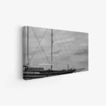 لوحة بحرية بتدرجات الرمادي، تظهر قاربًا بأشرعة مرتفعة تحت سماء غائمة، تعكس أجواء هادئة، لوحات مناظر طبيعية، لوحات كانفاس.
